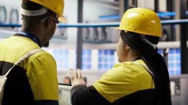 Bilişim personeli güneş paneli üretim hattı ekipmanlarını denetliyor. Otomatik endüstri 4.0 fabrikasında fotovoltaik montaj sistemleri kuran, beyin fırtınası yapan iş arkadaşları, kamera B