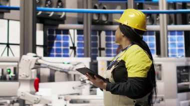 Güneş enerjisi kurulum sürecini denetleyen teknisyenler, otomatik makinelerin sorun çıkarması, yenilenebilir enerji üretim tesisinde robotik kolların kalibre edilmesi, kamera B