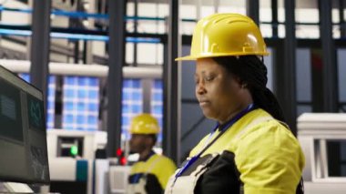 Akıllı bir fabrika uzmanı olan kadın otomatik iş akışlarını uygulamak için bilgisayar kullanır. Afrikalı Amerikalı teknisyen sensörleri B kamerasına entegre etmek için 4.0 sanayideki bilgisayarı kullanıyor.