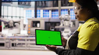 Güvenilirliği sağlamak için otomatik sistemleri test etmek için yeşil ekran tableti kullanan akıllı bir fabrika uzmanı. Endüstri 4.0 bitki teknisyeni krom anahtar cihazını kullanarak darboğazları tespit edip optimize ediyor, kamera A