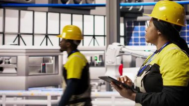 Yüksek teknoloji makinelerini ayarlamak ve sensör verilerini analiz etmek için tablet uygulamasını kullanan akıllı üretim fabrikası mühendisi. Mühendis fotovoltaik montaj ekipmanlarını sorunlu çekmek için dijital cihaz kullanıyor. Kamera A