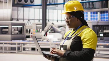 Laptop klavyesinde daktilo kullanan akıllı bir fabrika uzmanı güvenilirliğini sağlamak için otomatik sistemleri test ediyor. Endüstri 4.0 fabrika teknisyeni, darboğazları belirlemek ve optimize etmek için not defteri kullanıyor. Kamera A