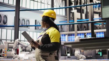 Akıllı fabrikadaki gülümseyen mühendis tablet kullanarak tahmin yürüterek IoT sensör verilerini analiz ediyor. Fotovoltaik sistemlerin işlevsel güvenilirliğini yöneten endüstriyel fabrika işçisi, kamera A