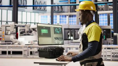 Bilgisayar klavyesinde yazan akıllı bir fabrika çalışanı otomatik sistemleri test ediyor, bakım yapıyor. Endüstri 4.0 fabrika çalışanı, bilgisayar kullanarak ekipmanları denetliyor ve hataları onarıyor, kamera A