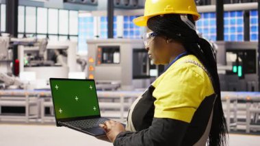 Fabrika mühendisi yeşil ekranda yazı yazıyor, üretim hatlarını izliyor. Endüstri 4.0 fabrikasındaki kadın makinelerin krom anahtar maket defteri ve kamera A 'yı kullanarak optimal verimlilikte çalışmasını sağlıyor.