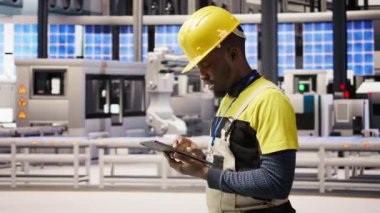 Güneş panelleri fabrikasındaki teknisyen, IoT sensör verilerini analiz etmek için tablet kullanıyor. Fotovoltaik sistemlerin işlevsel güvenilirliğini yöneten sanayi 4.0 bitki uzmanı cihaz, kamera A