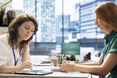 Kariyerinde ilerlemek isteyen iş görüşmesi adayı, tablet kullanarak İK çalışanı ile konuşmak. Kadın, üst düzey şirket pozisyonu için işe alınmak üzere CV 'sini kontrol ediyor.