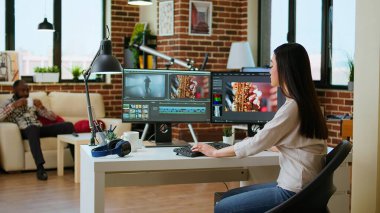 Freelancer Asyalı kadın video yapımcısı bir film projesinde çalışıyor, çift monitörlü çoklu görev, yazılım düzenleme ve çalışma alanında renk çarkı. Film kurgu endüstrisi. Kamera A.