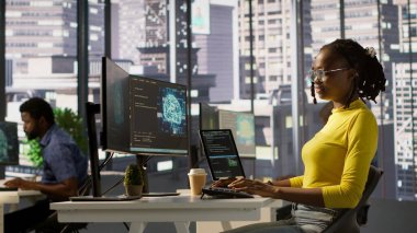 Yazılım mühendisi hataları düzeltmek için kod incelemesi yapar, yapay istihbarat şirketi yazılımıyla teknik sorunları tanımlar. Afro-Amerikalı kadın AI, kamera A kullanarak hata ayıklama ve optimize etme kodu kullanıyor.