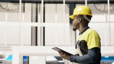 Elinde tablet tutan bir görevli fabrikada yürüyor, sistemleri denetliyor, ekipmanların en uygun verimlilikte çalışmasını sağlıyor. Sanayi fabrikası elektrikçisi tesis altyapısını denetliyor, kamera B