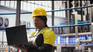 Sektör 4.0 fabrikasında çalışan bir kadın, bakım prosedürlerini takip ederek defter kullanıyor. Akıllı fabrika çalışanı dizüstü bilgisayardaki verileri analiz ederek dişli arızalarını öngörüyor, kamera A