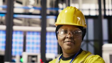 Endüstriyel santraldeki gülümseyen teknisyenin portresi güneş enerjisi kurulum sürecini denetliyor. Yenilenebilir enerji üretim tesisinde otomatikleştirilmiş robotik kolları kalibre eden mutlu işçi, kamera B