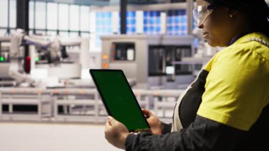 Fabrikadaki mühendisin bakım için kullandığı yeşil ekran tabletini kapatın, IoT sensör verilerini analiz edin. Renkli anahtar cihazı kullanarak fotovoltaik sistemleri yöneten endüstriyel fabrika işçisi, kamera A