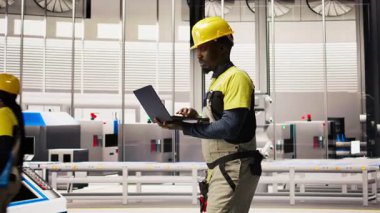 Otomatik çevre dostu fabrikada fotovoltaik montaj sistemlerinin korunması için dizüstü bilgisayar kullanarak güneş paneli üretim hatlarını inceleyen mühendis, kamera A