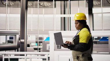 Uzman, yenilenebilir enerji üreten sanayi 4.0 fabrikasında rutin teftişler yapmak için dizüstü bilgisayar kullanıyor. Fotovoltaik teknisyeni akıllı fabrika test ekipmanları Not defteri, kamera A kullanarak