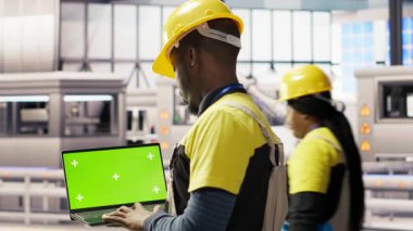 Akıllı fabrikadaki mühendis IoT sensör verilerini analiz etmek için yeşil ekran dizüstü bilgisayar kullanıyor. Endüstri 4.0 bitkisel uzmanlık sistemi tanımlaması krom tuşlu model defter üzerinde duraklama süresini azaltmak için B kamerası