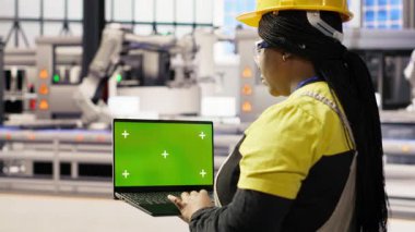 Yenilenebilir enerji endüstrisi 4.0 tesisinde yeşil ekran dizüstü bilgisayar kullanan bir uzman. Fotovoltaik teknisyeni. Akıllı fabrika test ekipmanları. Krom anahtar defteri, kamera B.