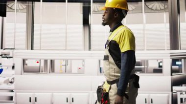 Fabrikada yürüyen, güneş paneli üretim ekipmanlarını denetleyen bir teknisyen. Otomatik endüstriyel tesiste fotovoltaik montaj sistemleri düzenleyen mühendislik uzmanı, kamera A