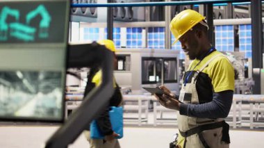 Mühendis, güneş paneli üretim hattı ekipmanlarını tablet uygulaması kullanarak denetliyor. İşçi dijital cihaz uygulaması, kamera A kullanarak otomatik sanayi 4.0 fabrikasında fotovoltaik montaj sistemleri kuruyor.