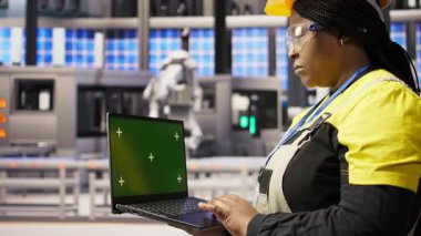 Yenilenebilir enerji endüstrisi 4.0 tesisinde yeşil ekran dizüstü bilgisayar kullanan bir uzman. Fotovoltaik teknisyeni. Akıllı fabrika test ekipmanları. Krom anahtar defteri, kamera A kullanıyor.