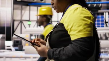 Akıllı güneş enerjisi üretim tesisinde mühendis yüksek teknoloji makinelerini ayarlıyor ve sensör verilerini analiz ediyor. Mühendis sorun çıkaran fotovoltaik montaj ekipmanı, kamera.