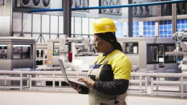 Güneş panelleri fabrika mühendisi ekipman arızalarını tahmin etmek için performans verilerini dizüstü bilgisayarla analiz ediyor. Kapatma süresini en aza indirmek için bakım prosedürlerini takip eden fotovoltaik fabrika işçisi, kamera A