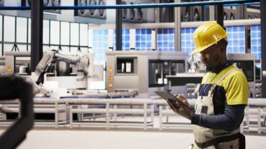 Otomatik sistemleri test eden akıllı bir fabrika uzmanı. Operasyonel bütünlüğü izliyor. Endüstri 4.0 tesis teknisyeni hasar tespiti ve onarım ekipmanları, kamera A