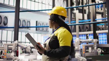 Akıllı güneş panelleri fabrika mühendisi üretim hatlarını denetlemek için tablet kullanıyor. Sektör 4.0 fotovoltaik fabrikasındaki kadın makinelerin en uygun verimlilikte çalışmasını sağlar. Cihaz, kamera A kullanarak.