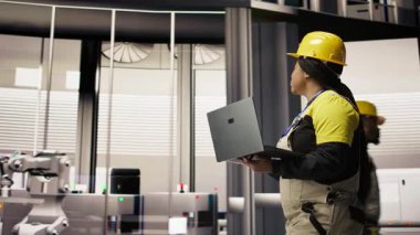 Akıllı fabrika mekanik bilgisayar operasyonları ve enerji tüketimini dizüstü bilgisayarla izlemek. Sektör 4.0 'da yürüyen tamirci elinde not defteri, teknik destek sağlıyor, kamera A