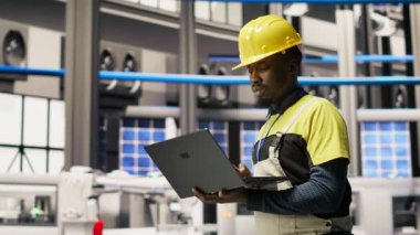 Endüstriyel santraldeki teknisyen güneş enerjisi kurulum sürecini denetliyor, sorun çıkarma hataları. Yenilenebilir enerji üretim tesisi çalışanı otomatik robotik kolları kalibre ediyor, kamera B