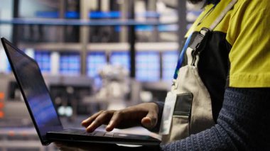 Akıllı fabrikadaki mühendis, dizüstü bilgisayar yazılımı kullanarak kalite kontrolü sağlayan robot montaj hatlarını denetliyor. İşçi otomatik taşıma sistemlerini not defteri programı ve kamera kullanarak izliyor.