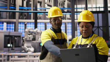 Yüksek teknolojili makineleri ayarlamak ve sensör verilerini analiz etmek için dizüstü bilgisayar kullanan akıllı bir fabrika mühendisliği ekibi. İş yerindeki ekip çalışanları montaj ekipmanları, kamera A