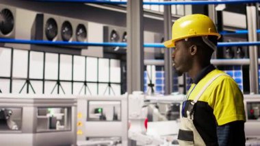 Elinde alet çantası olan bir adam fabrikada yürüyor, sistemleri denetliyor, makinelerin en uygun verimlilikte çalıştığından emin oluyor. Sanayi 4.0 fabrika tamircisi altyapıyı denetliyor, işlemleri sürdürüyor, kamera A