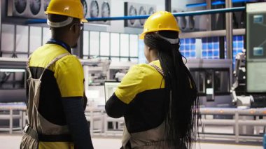 Bilişim personeli güneş paneli üretim hattı ekipmanlarını denetliyor. Otomatik endüstri 4.0 fabrikasında fotovoltaik montaj sistemleri kuran, beyin fırtınası yapan iş arkadaşları, kamera A