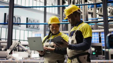 Güneş panelleri fabrika mühendisliği ekibi dişli arızalarını tahmin etmek için dizüstü bilgisayardaki performans verilerini analiz ediyor. Takım çalışması fotovoltaik, bakım prosedürlerini takip eden meslektaşları, kamera A