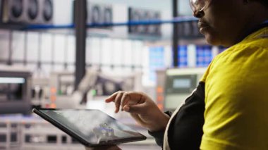 Endüstri 4.0 sanayi mühendisi tablet üzerinde CAD uygulaması kullanan yeni robotik makineler tasarlıyor. Akıllı fabrika işçisi tesis zemininde ekipman düzenini optimize ediyor, kamera A yakın plan