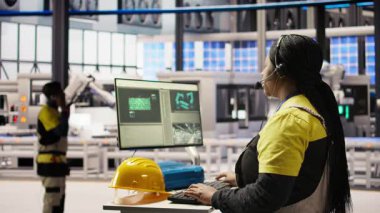 Otomatik üretim fabrikası uzmanı canlı üretim verilerini analiz ediyor, kulaklık mikrofonunu kullanarak mühendislere robotik silahlar, taşıma bantları ve fotovoltaik sistemler, kamera A hakkında bilgi aktarıyor.