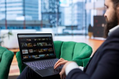 Bükreş, Romanya - 30 Temmuz 2024 - İşletme CEO 'su Netflix' in ofisindeki yayın platformunda iş yerinde zaman öldürmek için iyi bir film veya televizyon programı arıyor. Başarılı bir girişimci..