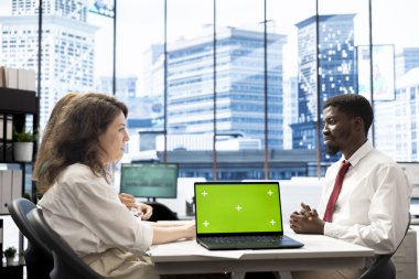 İK uzmanlarından oluşan bir ekip, yeşil ekranlı dizüstü bilgisayar kullanarak adaylarla iş teklifleri ve maaş paketleri üzerinde görüşüyor. Meslektaşlar başvuru sahibinin özgeçmişini ve kapağını analiz ederken, maket defterini kullanır