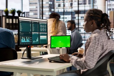 Ofisteki Afrikalı Amerikalı iş kadını finansal verileri analiz ediyor ve şirket başarısı için büyüme stratejileri geliştiriyor. Önemli görevleri yöneten analist.