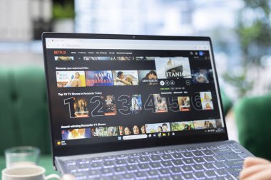 Bükreş, Romanya - 30 Temmuz 2024 - Girişimci Netflix yayın hizmetinde, ofiste rahatlama için bir film seçmek üzere kaydırma yapıyor. Genç CEO şirketinde eğleniyor..