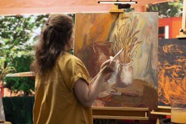 Kırsal bir atölyede, sanatçı bir paletin üzerine çeşitli suluboya boyalar karıştırarak tuval üzerinde renkli bir başyapıt yaratır. Fırçayla resim yapan ve yeteneğini ve sanat eserlerini gösteren bir kadın..