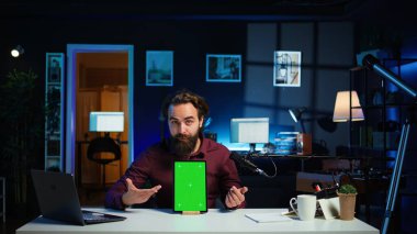 Teknoloji uzmanı stüdyoda çekim yapan izleyicilere düşük bütçeli krom anahtar tableti sunuyor. Yeşil ekran dijital aygıtını inceleyen viral içerik oluşturucu, kamera B