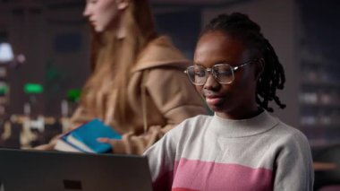 Siyahi kız üniversite kütüphanesinde lisans diploması için eğitim araştırma koleksiyonunu ve genel veritabanını bilgi için kullanıyor. Kağıt için celp kağıdı topluyorum. Kamera A.