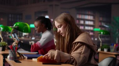 Kaba genç kız kampüs kütüphanesinde telefonla konuşuyor ve öğrencileri rahatsız ediyor, çok gürültü yapıyor. İnsanlar sessiz kalmak istiyor, öğrenirken odaklanamıyor ve konsantrasyonunu kaybediyor. Kamera A.