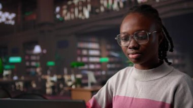 Siyahi kız üniversite kütüphanesinde lisans diploması için eğitim araştırma koleksiyonunu ve genel veritabanını bilgi için kullanıyor. Kağıt için celp kağıdı topluyorum. Kamera B.