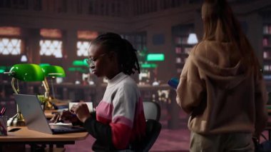 Üniversite öğrencisi kampüs kütüphanesinde bir arkadaşıyla el yazısı notlarını tamamlamak için sınav hazırlığı yapıyor. Veritabanından bilgi paylaşan kızlar. Kamera A.