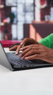 Dikey Video Freelancer, internet günlüğü için dizüstü bilgisayarıyla hikaye anlatma üzerine yazılar yazıyor ve çalışıyor. Siyahi adam sosyal medya paylaşımları yazıyor, birden fazla iş yapıyor. Kamera B