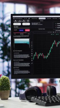 Dikey Video Boş çalışma alanı masaüstü çalışma günü şık bir dairede borsa trendleri ticareti. Yatırım rakamlarını ve mum çubuğu grafiklerini izlemek için kullanılan bilgisayar, rahat bir ortam.