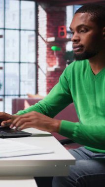 Dikey Video Siyah tele-muhabiri masanın altından bacağını sallıyor ve kararsız davranıyor, görev teslim tarihine yetişmeye çalışırken gergin ve gergin hissediyor. Genç yetişkin hiperaktivite yüzünden huzursuz.